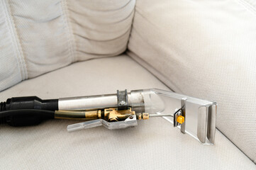 Cleaning tool for upholstery maintenance on a beige couch during daylight