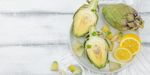 Fresh green artichokes cooking on wooden background. Traditional seasonal ingredients