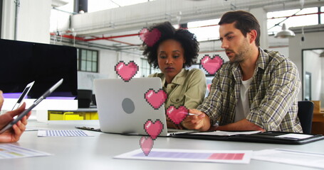 Reviewing colleagues examining color charts in modern office, with silver laptop smartphone binder