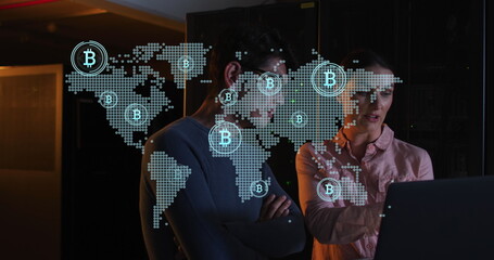 Pointing adult white woman wearing pink shirt showing data on laptop in data center, bitcoin map