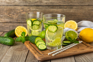 Cucumber water with lemon, lime and mint on a wooden table. Water infused with sliced...