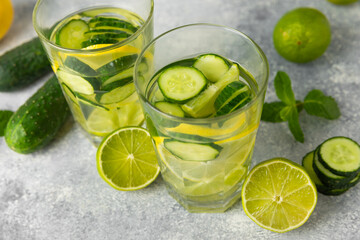 Cucumber water with lemon, lime and mint on a wooden table. Water infused with sliced ​​cucumber in a drinking glass. Tonic refreshing drink. Cucumber lemonade.Summer natural cooling drink.Copy space