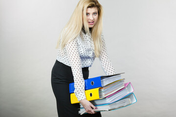 Woman holding heavy colorful binders with documents