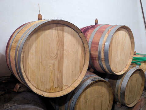 Barris de carvalho empilhados em adega para o armazenamento de vinho tinto
