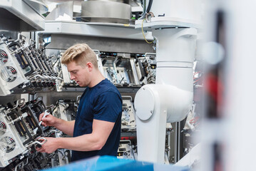 Technician working on industrial robots in a production hall