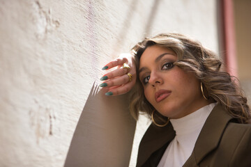 Portrait of young, pretty, blonde woman, wearing a green jacket, posing looking at the camera, sad...