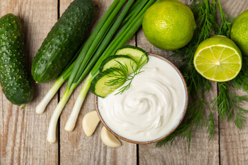 Cucumber sour cream tzatziki sauce on a wooden table.Tartar sauce. Traditional delicious appetizer. yogurt sauce. Tzatziki with ingredients cucumber, garlic,dill,lemon,mint. salad dressing.Copy space