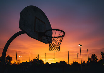 Basketball hoop silhouette against vivid sunset sky sport concept