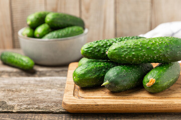 Cucumber on wooden background. Slice of cucumber on background. Fresh organic green cucumbers gherkin. Vegan. Salad ingredient. Farm vegetables. Cut vegetables with knife. Space for text. Copy space