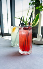 Cold lingonberry drink on restaurant table. Iced cowberry tea, refreshing cranberry cocktail