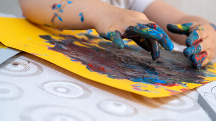 Joyful little girl engaging in fun educational finger painting activity, exploring creativity with vibrant colorful paints and learning through playful art exploration