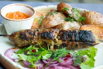 Georgian lula kebab plate. Bbq skewer, traditional barbecue dish with baked potatoes, sauce