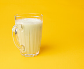 Vanilla milk shake in glass. Milkshake on yellow background, white whey protein smoothie