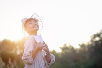 Happy woman lying on green grass reading a book in the park (outdoors)
