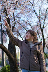 portrait of a teenage girl in a spring park touches flowers, flowering trees