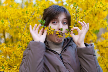 portrait of a girl on the background of yellow forsythia flowers, spring nature and blossoms