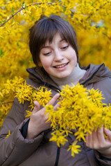 Naklejka premium portrait of a girl on the background of yellow forsythia flowers, spring nature and blossoms