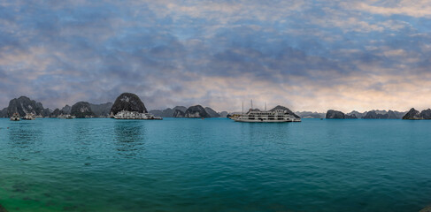 Fototapeta premium Halong Ha Long Bay Hanoi this Vietnamese wonder is littered with mountains and Rock cliffs popping out of the ocean, lush green mountains in Vietnam