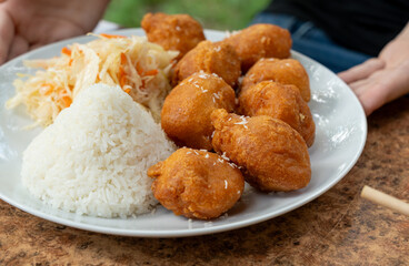 Fried chicken balls with rice and fresh cabbage salad closeup. Deep fried dough balls