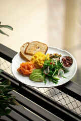 Set breakfast with scramble egg fish and avocado on handrail