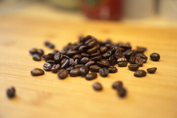 Roasted coffee beans on a wooden surface. long_title:A close-up view of freshly roasted coffee beans scattered across a warm, wooden table, showcasing