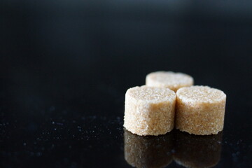 Brown sugar cubes shimmer under the light, revealing their perfect cubic shapes and delicate crystals. 