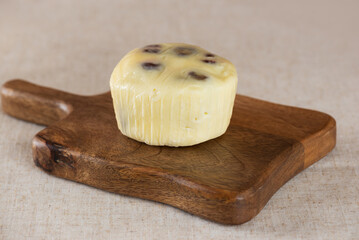 Hand of farm cheese with dates and strawberries on a wooden board.