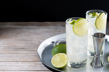Gin Fizz cocktail with lime on wooden table and black background. Copy space