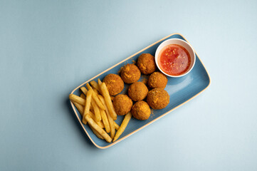 Cheddar Stuffed Button Mushrooms filled with aged cheddar, crumb-fried to golden perfection, served with chilli-roasted plum sauce and crispy fries on a blue plate against a blue background.