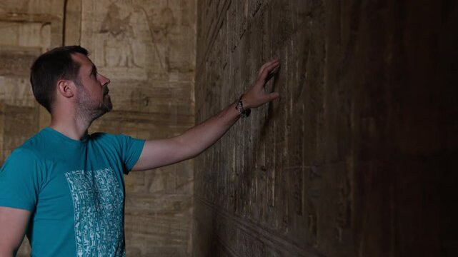 Person exploring ancient carvings at Dendera Temple in Egypt, observing the artwork