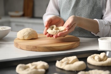 Woman shaping pretzels at table in kitchen, closeup