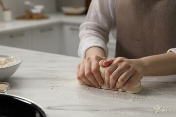 Making pretzels. Woman kneading dough at table in kitchen, closeup