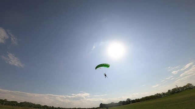 A skydiver with a green parachute lands