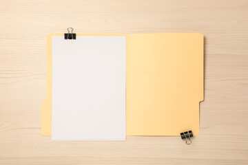 Paper file folder with blank sheets and binder clips on wooden table, top view