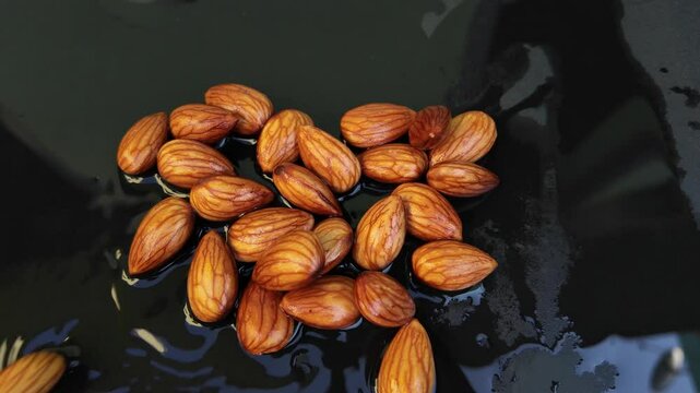 Almonds falling on black chopping board for smoothie making