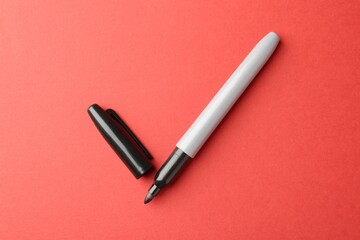 One black marker on red background, top view