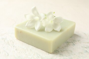 Bar of soap and jasmine flowers on light table, closeup
