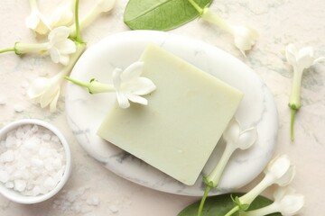 Bar of soap, sea salt and jasmine flowers on light table, flat lay