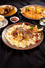 biryani and smoked barbeque mutton thigh served on brown plate with pickles, tomato, cucumber and onion. Perfect for menu, advertising or commercial use