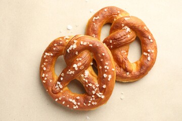 Tasty pretzels with salt on beige background, flat lay