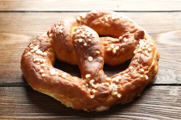Tasty pretzel with salt on wooden table, closeup