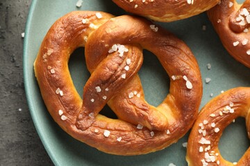 Tasty pretzels with salt on grey table, top view