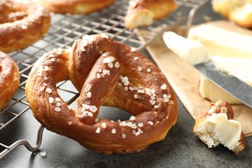 Tasty pretzels with salt and butter on grey table, closeup