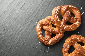 Tasty pretzels with salt on black table, flat lay. Space for text