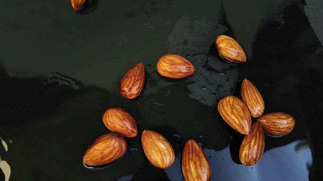 Slow Motion of Falling Almonds into Dark water background , almonds falling cinematic scene