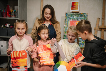 Children painted pictures in a workshop in art class. Happy children showing their landscape drawings in art class. Art lesson. Education and learning concept.