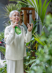 Obraz premium Elderly woman taking care of houseplants