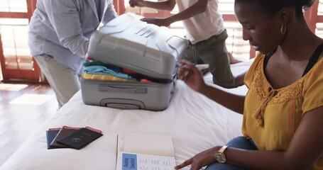 Family packing suitcase on bed, preparing for vacation with passports ready, at home