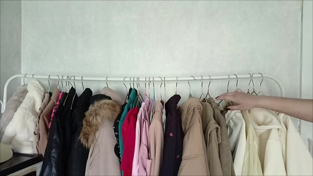 A woman's hand picks up a hanger with a yellow shirt from the counter. Dressing room. clothing store. The concept of women choosing clothes. There is a sale in the store.
