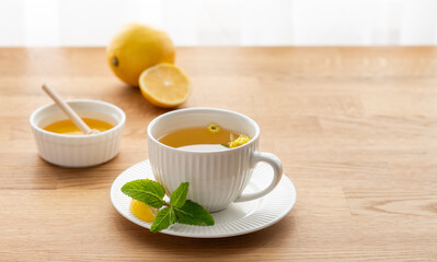 Cup of herbal tea with lemon, honey and mint on wooden tabletop
